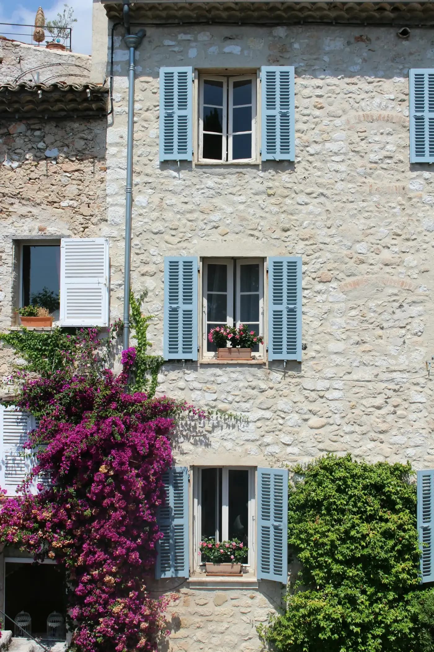 La façade en pierre du mas et ses volets bleus